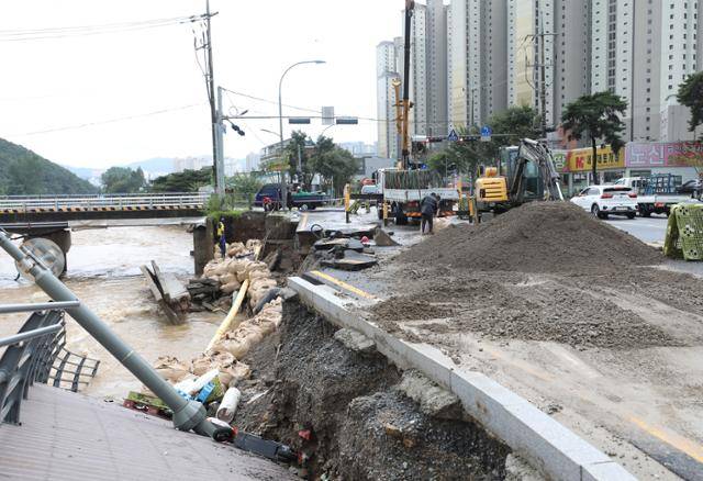 9일 오후 경기 용인시 수지구 동천동 동막천이 범람하면서 도로가 침하되고 도로변에 조성된 데크 길이 무너져 내려 관계자들이 복구작업을 하고 있다.뉴스1