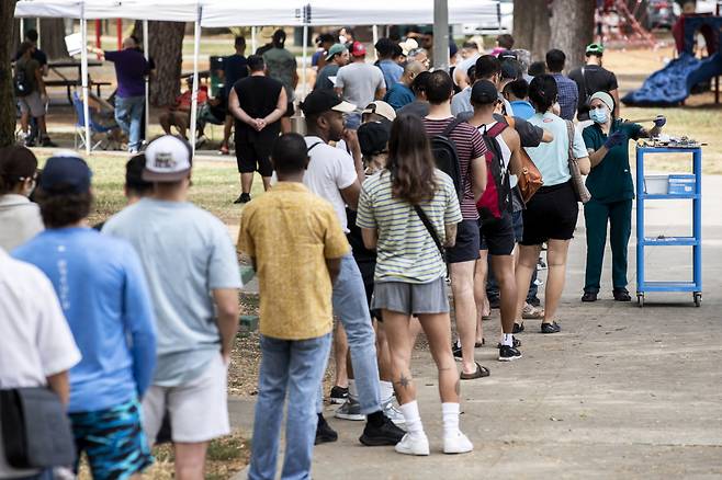 4일(현지시간) 미국 캘리포니아주 로스앤젤레스의 한 공원에서 간호사가 원숭이두창 백신을 접종하기 위해 줄지어 선 시민들에게 예진표를 나눠주고 있다. 미국의 원숭이두창 감염자는 지난 5월 처음 발생한 이후 현재 6천 명을 넘어섰으며, 바이든 행정부는 이날 원숭이두창에 대해 공중보건 비상사태를 선포했다. [연합]