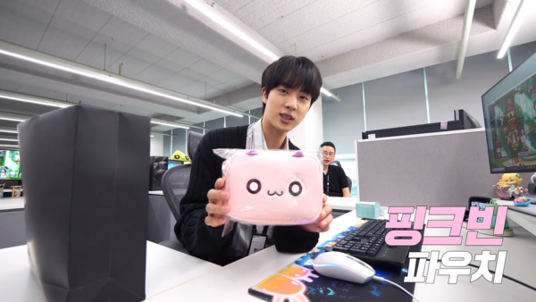 웰컴키트에 담긴 구성품을 보여주는 진의 모습