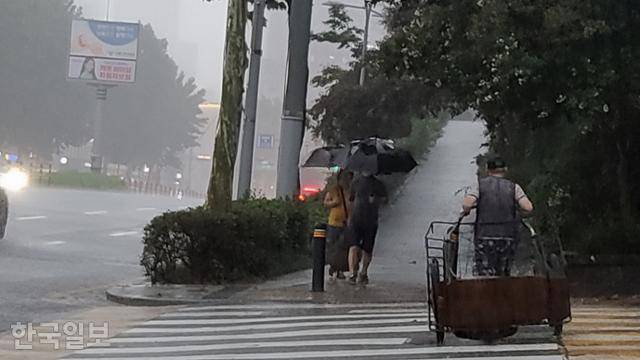 장대비가 쏟아지던 8일 저녁 서울 동작구 사당동에서 폐지를 줍는 한 노인이 빈 리어카를 끌고 횡단보도를 건너고 있다. 나광현 기자