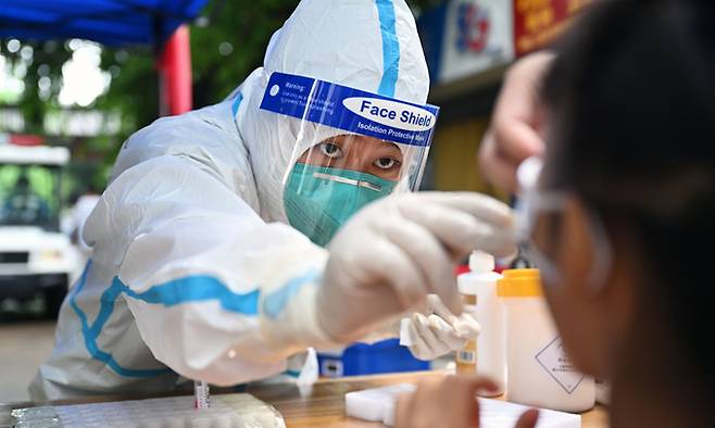 코로나19 확산으로 봉쇄 조치가 내려진 중국 하이난성 싼야에 파견된 허난성 의료인이 지난 11일 핵산 검사를 위해 현지 주민의 검체를 채취하고 있다. 신화연합뉴스