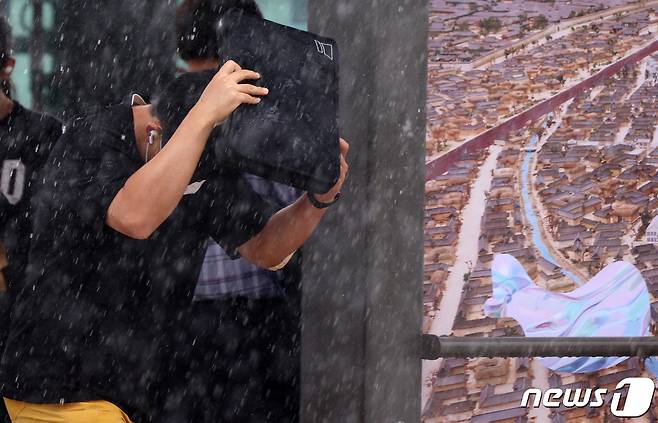 소나기가 내린 6일 서울 종로구 광화문 앞 삼거리도로에서 한 시민이 가방으로 비를 피하며 발걸음을 재촉하고 있다. 2022.8.6/뉴스1 ⓒ News1 이동해 기자