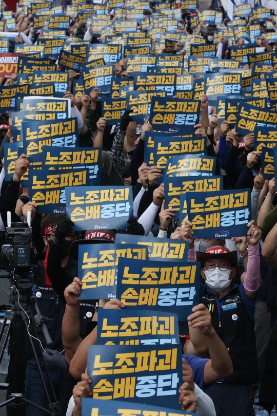 18일 민주노총 공공운수노조 조합원들이 서울 청담동 하이트진로 본사 앞에서 열린 화물연대 고공농성투쟁 승리 결의대회에서 팻말을 들고 구호를 외치고 있다. 연합뉴스