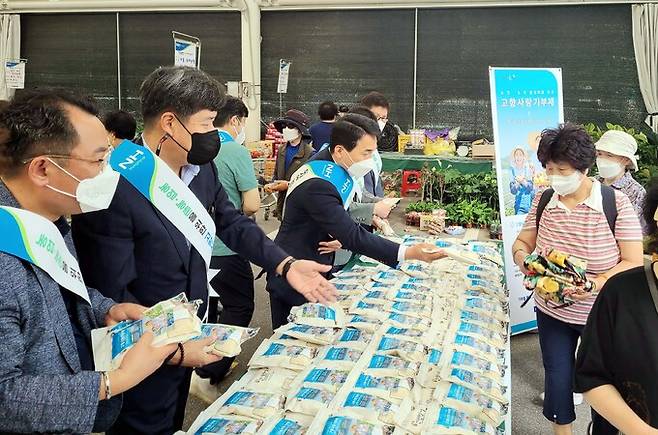 서울농협이 직거래장터 방문 고객들에게 고향사랑기부제를 안내하며 쌀 사은품을 나눠주고 있다. (왼쪽부터 한성식 서울노조위원장, 황준구 서울지역본부장, 임순혁 서울영업본부장) 서울농협 제공