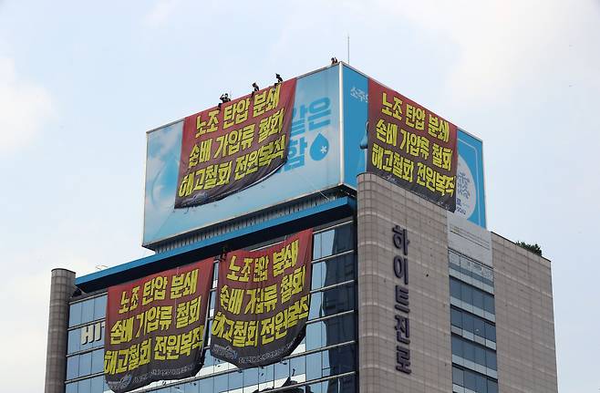하이트진로 본사 옥상에서 고공 농성을 하고 있는 민주노총 공공운수노조 화물연대 조합원들이 18일 오후 서울 강남구 하이트진로 본사 앞에서 열린 '고공 농성 투쟁 승리 결의 대회'를 지켜보고 있다. /뉴시스