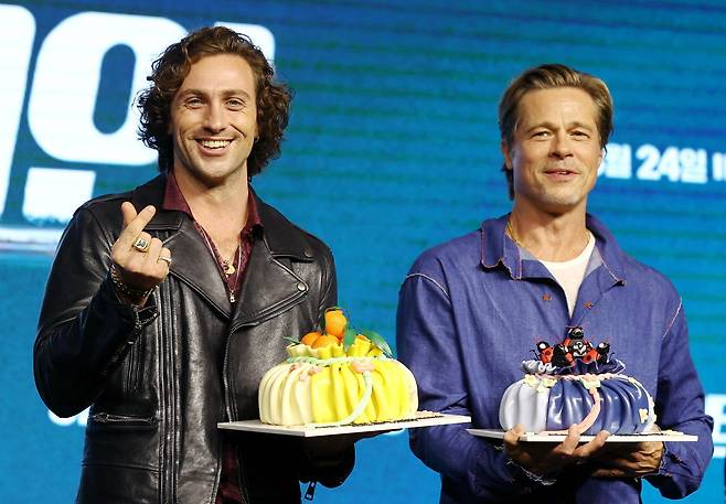 Actors Brad Pitt (right) and Aaron Taylor-Johnson pose with cakes shaped like Korean fortune pouches called “bokjumeoni” before a press conference held at Conrad Seoul in Yeouido, Seoul, on Friday. (Yonhap)