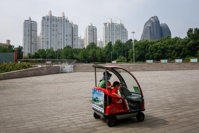 17일 중국 베이징 시내의 한 공원에서 한 여성이 자녀들과 함께 전기차를 타고 있다. 중국 정부는 이날 '인구 절벽' 위기를 극복하기 위한 범정부 차원의 주택·보육·취업 종합대책을 내놨다. 베이징=EPA 연합뉴스