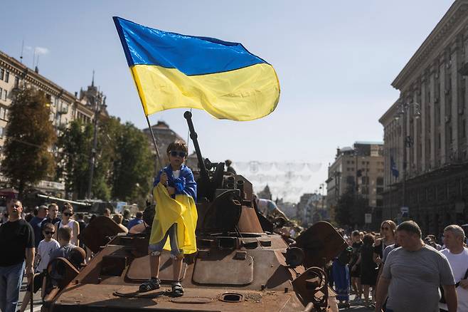 파괴된 러시아 장갑차량에서 국기 흔드는 우크라이나 어린이 / 사진=연합뉴스