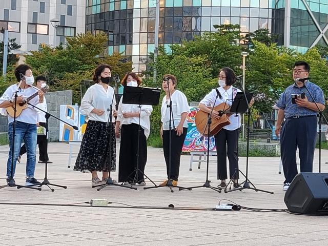 장애인 자녀를 둔 부모들로 구성된 맘마스 노래패가 20일 공항철도 운서역 광장에서 '길가에 앉아서'를 부르고 있다. 국민엔젤스앙상블 제공