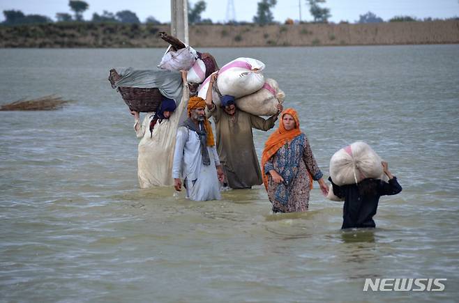 [자파라바드=AP/뉴시스] 24일(현지시간) 파키스탄 남서부 발루치스탄주 자파라바드에서 한 이재민 가족이 폭우로 발생한 홍수 침수 지역을 지나가고 있다. 파키스탄 당국은 지난 6월 중순부터 내린 폭우에 따른 돌발 홍수와 산사태 등으로 지금까지 파키스탄 전역에서 903명이 숨지고 약 5만 명의 이재민이 발생했다고 밝혔다. 2022.08.25.