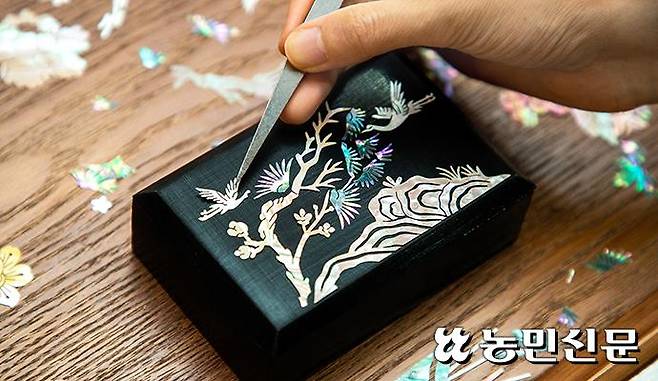 풀칠한 명함보관함에 조개류 껍데기를 잘라 만든 자개 학과 소나무·바위를 하나씩 얹어나가자 한폭의 자개 동양화가 펼쳐진다. 현진 기자