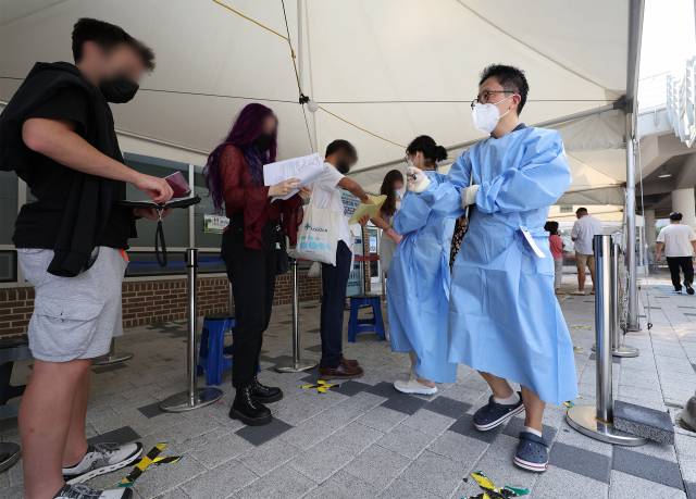 26일 오전 서울 마포구보건소에 마련된 선별진료소에서 외국인들이 검사를 받기 위해 줄을 서고 있다. 중앙방역대책본부에 따르면 이날 0시 기준 신규확진자 수는 10만1140명을 기록했다. 연합뉴스