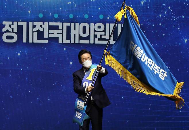 더불어민주당 이재명 신임 당 대표가 28일 서울 송파구 올림픽 체조경기장에서 열린 제5차 정기전국대의원대회에서 당 대표로 선출된 뒤 당기를 흔들고 있다. /연합뉴스