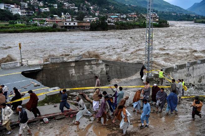 27일(현지시간) 파키스탄 북부 스와트 밸리의 마디안 지역에서 주민들이 불어난 물을 피해 대피하고 있다. AFP=연합뉴스