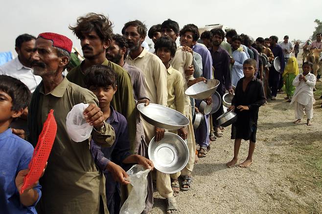 27일(현지시간) 파키스탄 주민들이 식기를 들고 구호물품을 기다리고 있다. AP=연합뉴스