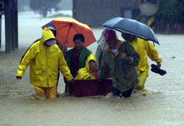 2002년 8월 31일 태풍 루사가 한반도를 관통하며 집중호우를 뿌리는 가운데 강원 강릉시 장현저수지 제방의 붕괴가 우려되자 하류지역 주민들이 거동이 불편한 주민을 긴급히 구조하고 있다. 강릉=연합뉴스