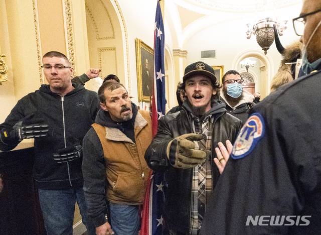 [워싱턴= AP/뉴시스] 지난 1월 6일 미 의사당 상원 회의장에 난입해서 의회경찰과 설전을 벌이고 있는 남부군 깃발든  케빈 시프리드의 모습( 가운데).  워싱턴 검찰은 남부군의 전투깃발을 든 사진으로 델라웨어에서 온 그와 아들의 신원을 확인해 체포할 수 있었다고 밝혔다.
