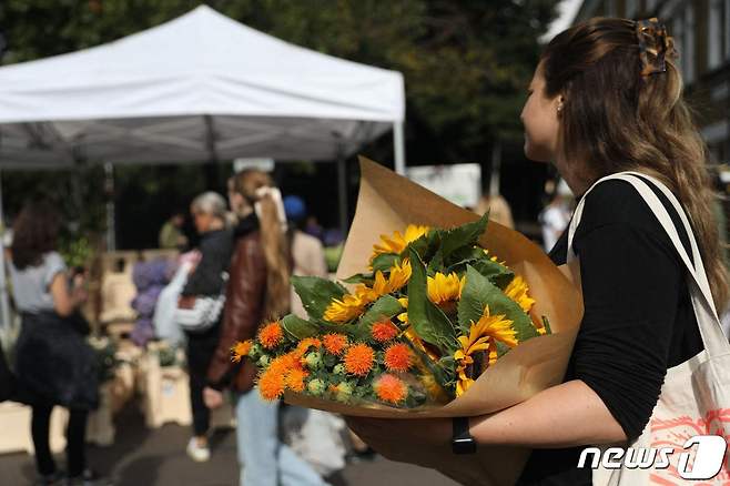 영국 런던의 컬럼비아 로드 꽃시장에서 11일(현지시간) 한 시민이 고(故) 엘리자베스 2세 여왕을 추모하기 위해 꽃다발을 구매하고 있다. ⓒ AFP=뉴스1 ⓒ News1 김예슬 기자