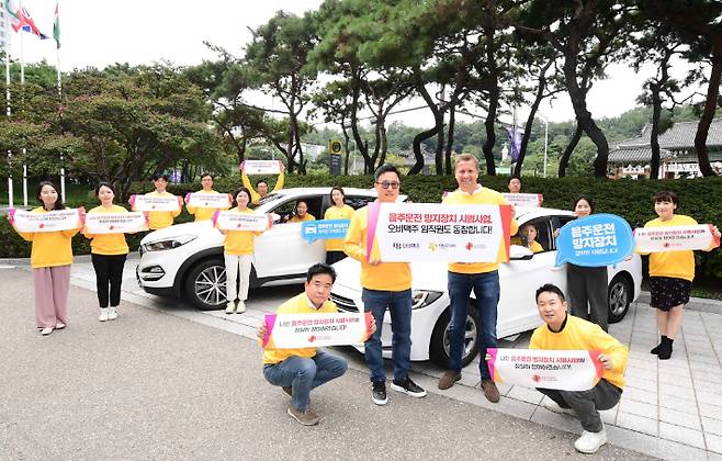 14일 강남구 삼성동 오비맥주 본사 앞에서 '음주운전방지장치'를 설치하고 시범사업에 참여하는 임직원과 함께 기념사진을 찍고 있다. (맨 앞 서있는 분 왼쪽부터 구자범 오비맥주 법무정책홍보 부사장, 배하준 오비맥주 대표 오비맥주 제공