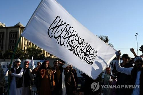 8월 31일 미군 철수 1년을 기념해 탈레반 상징 깃발을 들고 환호하는 대원 [AFP 연합뉴스 자료사진. 재판매 및 DB 금지]