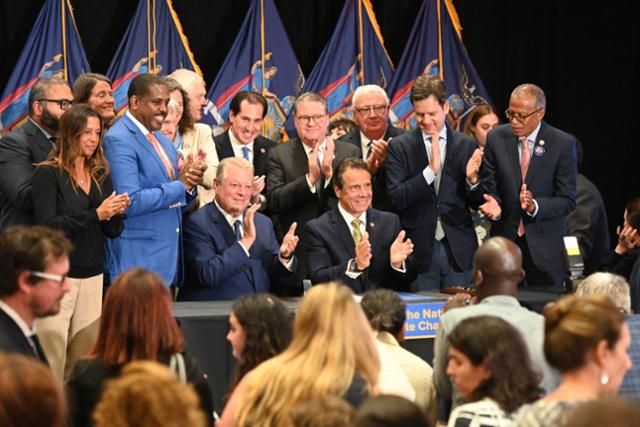2019년 7월 앤드류 쿠오모 전 뉴욕주지사(사진 오른쪽에서 세 번째)가 뉴욕주 기후변화리더십 및 지역보호법안(CLCPA)에 서명한 뒤 박수를 치고 있습니다. 뉴욕주 제공