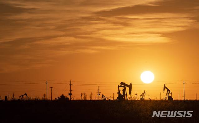 [골드스미스=AP/뉴시스]21일(현지시간) 미 텍사스주 골드스미스 인근 유정의 원유시추기 펌프잭들 뒤로 해가 지고 있다. 2021.04.22.