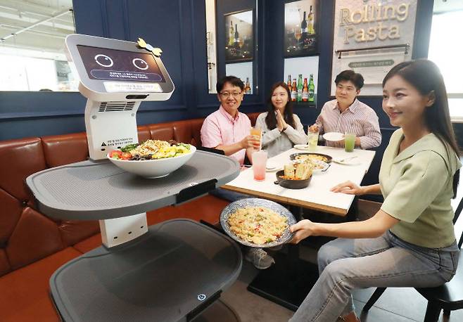 LG유플러스는 LG전자와 함께 로봇사업을 본격 추진하고 서빙-배송-안내 등 고객 접점에서 디지털혁신을 가속화한다고 22일 밝혔다. 사진은 서울 구로구 롤링파스타 매장에서 LG 클로이 서브봇이 가져온 음식을 손님이 꺼내는 모습.