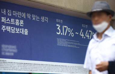 지난 18일 서울 시내 한 은행에 붙은 대출 관련 안내문 앞을 한 시민이 지나고 있다. 사진=연합뉴스.