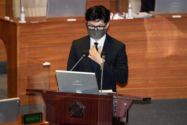 한동훈 법무부 장관이 19일 오후 서울 여의도 국회 본회의장에서 열린 정치분야 대정부질문에서 더불어민주당 김회재 의원의 질의에 답변하던 중 넥타이를 만지고 있다. 연합뉴스