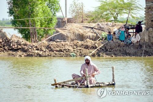 파키스탄 발루치스탄의 홍수로 물에 잠긴 마을에서 뗏목을 탄 주민. AFP 연합뉴스