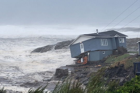 24일(현지시간) 캐나다 동부 해안을 강타한 폭풍에 뉴펀들랜드주 포트 오 바스크해안가의 주택이 위태롭게 서 있다. 로이터 연합뉴스