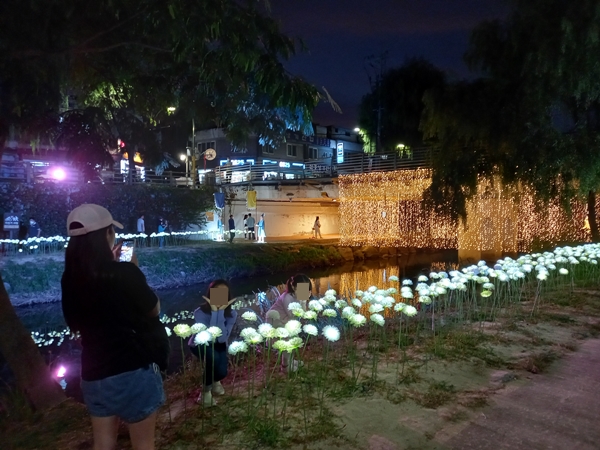 가족이 LED로 만든 꽃을 배경으로 사진을 찍고 있다.