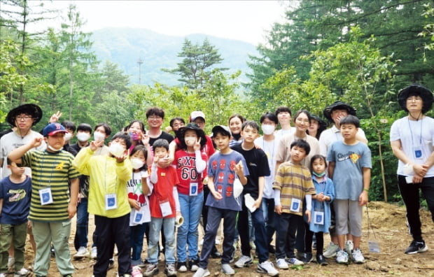 두나무 임직원과 가족들이 국립 양평 치유의숲에서 교통약자를 위한 작은 숲 조성 봉사활동을 마치고 기념사진을 찍고 있다.   두나무 제공