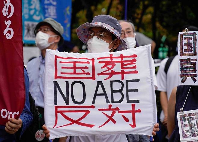 일본 도쿄에서 시위대가 27일 아베 신조 전 총리의 국장에 반대하는 팻말을 들고 있다. AP연합뉴스