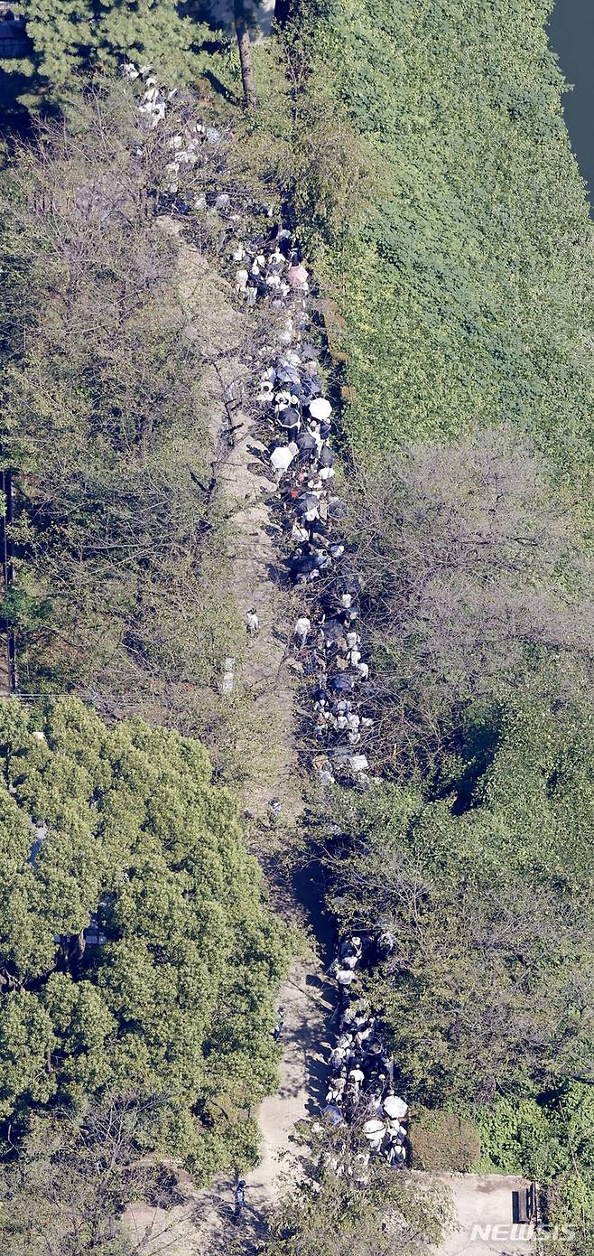 [도쿄=AP/뉴시스]27일 아베 신조 전 총리의 국장이 도쿄 니혼부도칸에서 열렸다. 일반 시민들이 인근 헌화대에 헌화하기 위해 줄을 서고 있다. 2022.09.27.