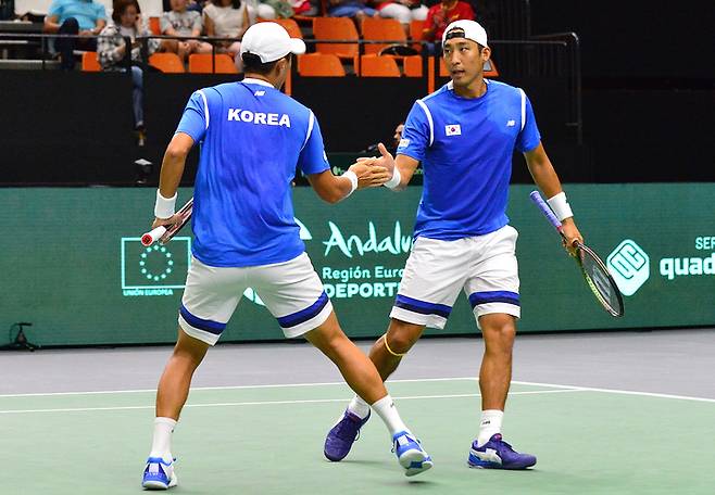 [서울=뉴시스] 한국 남자테니스 대표팀 송민규(왼쪽), 남지성이 13일(현지시간) 스페인 발렌시아에서 열린 2022 데이비스컵 파이널스 조별리그 1차전 한국과 캐나다의 경기 중에 하이파이브를 하고 있다. (사진=대한테니스협회 제공) 2022.09.14. photo@newsis.com *재판매 및 DB 금지