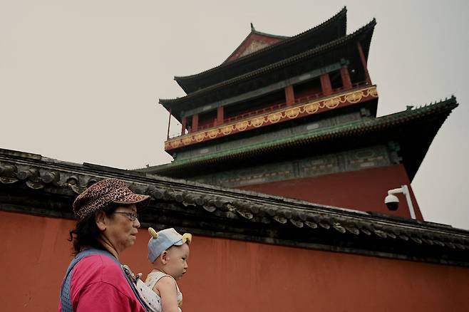 한 여성이 아기를 안고 중국 베이징 시내를 지나고 있다. /AFP연합