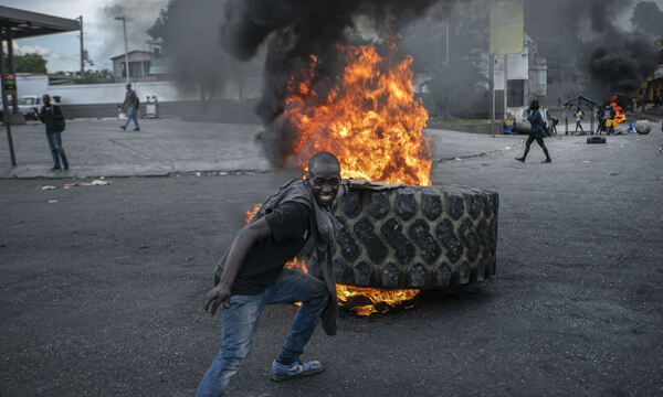 지난 16일(현지시간) 아이티의 수도 포르토프랭스에서 총리 퇴진 요구와 연료 가격 인상에 항의하는 시위 도중 한 시위자가 불타는 바리케이드에 타이어를 추가하고 있다. AP연합뉴스
