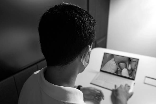 한 남성이 노트북으로 내성 발톱 환자의 발가락에 찬 고름을 빼내는 ‘더티 플레저’ 영상을 시청하고 있다. / 임화승 영상미디어 기자