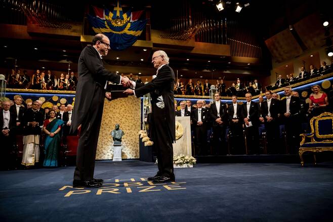 지난 2019년 노벨 경제학상 수상자로 선정된 마이클 크레머 미국 하버드대 교수가 같은 해  12월 10일 스웨덴 스톡홀름 콘서트홀에서 열린 노벨상 시상식에서 칼 구스타프 16세 국왕으로부터 상을 받고 있다. /노벨 미디어AB
