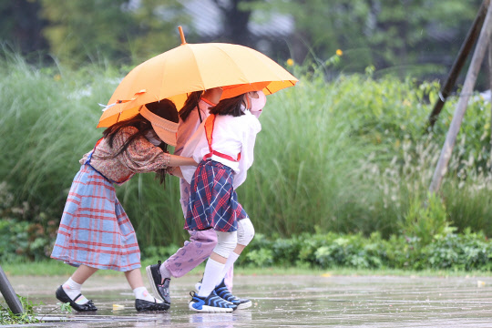 비가 내리는 지난달 23일 오전 서울시청 인근에서 어린이들이 함께 우산을 쓴 채 이동하고 있다. 연합뉴스