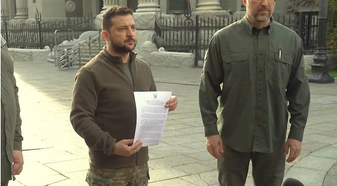 [서울=뉴시스]볼로디미르 젤렌스키 우크라이나 대통령은 30일(현지시간) 북대서양조약기구(NATO·나토) 가입 신청서에 서명했다고 발표했다. 그는 사전 녹화한 영상 메시지를 발표해 밝혔다. 젤렌스키 대통령이 신청서에 서명한 후 들어보이고 있다. 사진은 우크라이나 대통령실 공식 유튜브 채널 영상 갈무리. 2022.10.01. *DB 및 재판매 금지.