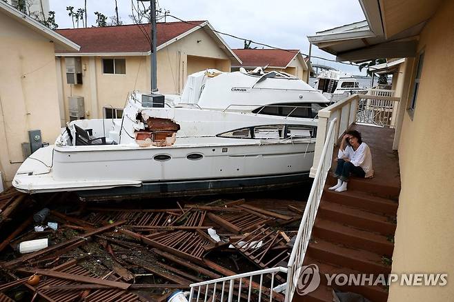 허리케인은 지나갔지만 앞으로는? (포트마이어스[미 플로리다주] AFP=연합뉴스) 2022년 9월 29일(현지시간) 허리케인 이언이 강타한 플로리다 포트마이어스의 주택가에서 주민 브렌다 브레넌이 아파트 앞까지 떠내려온 보트 앞에 시름에 빠진 채 앉아있다. 2022.10.1