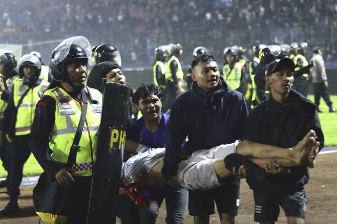 인도네시아 경찰들과 시민들이 부상당해 쓰러진 축구팬을 옮기고 있다. 사진=AP PHOTO