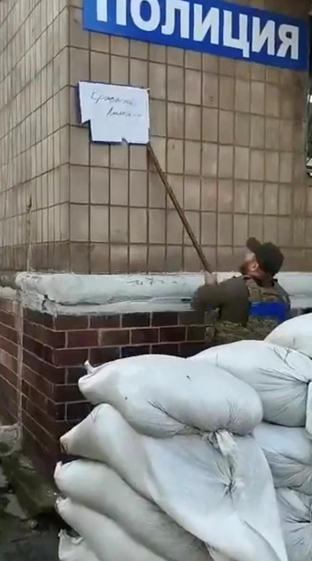 우크라이나 군인이 1일 다시 되찾은 도네츠크주 리만에서 경찰서 벽에 붙은 러시아군 표지판을 떼어내고 있다. 리만=로이터 연합뉴스