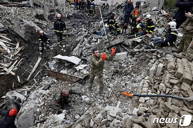 지난 9월28일(현지시간) 우크라이나 동부 하르키이주 이지움시에서 우크라이나 군과 소방 관계자들이 합동으로 러시아군 폭격에 무너진 방송국 건물 잔해를 뒤지며 민간인 주검을 찾기 위해 안간힘을 쓰고 있다. 한때 러시아군이 점령했던 이지움 일대는 최근 우크라이나군이 탈환에 성공했다. ⓒ 로이터=뉴스1 ⓒ News1 김성식 기자