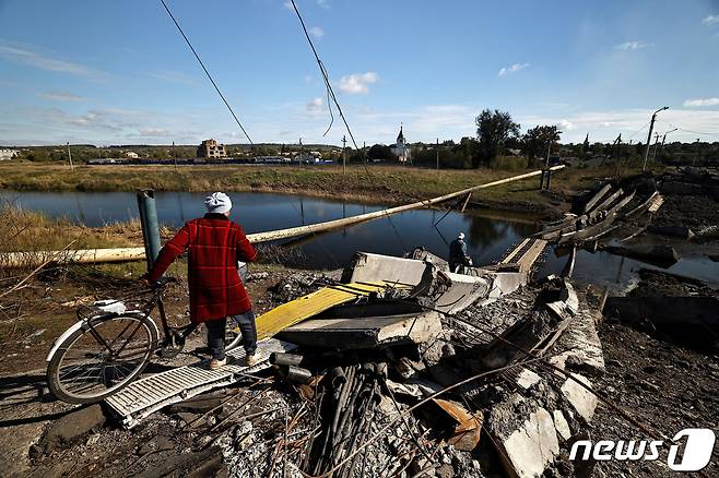 6일(현지시간) 우크라이나 도네츠크 바흐무트에서 러시아와 우크라이나군 교전으로 파괴된 다리 폐허를 통과하고 있는 한 주민. 2022.10.06/뉴스1 ⓒ 로이터=뉴스1 ⓒ News1 김민수 기자