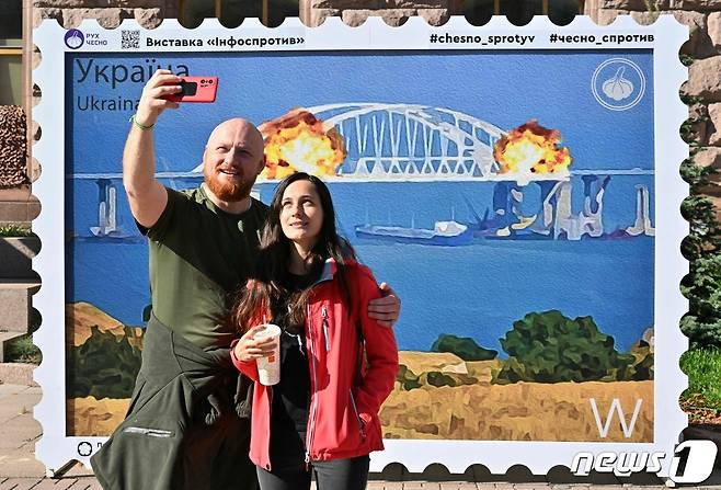 8일(현지시간) 한 커플이 크름대교 폭발 기념 우표 도안 앞에서 기념촬영을 하고 있다. ⓒ AFP=뉴스1 ⓒ News1 박형기 기자