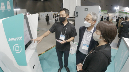 지난 6일부터 8일 일본 아이치현 국제전시장에서 열린 'SDGs 아이치 엑스포 2022' 티가이아 부스에서 관계자가 중고폰 매입 기기 '민팃' 기능을 설명하고 있다. <SK네트웍스 제공>