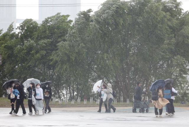 서울 반포 한강공원에서 10일 오후 돌풍을 타고 옆으로 몰아치는 비를 시민들이 우산으로 막고 있다. 연합뉴스